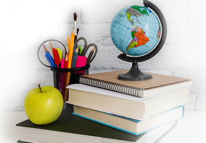 globus, jabłko, przybory do pisania stojące na książkach